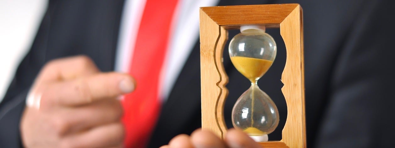Man in a suit with tie holding an hourglass